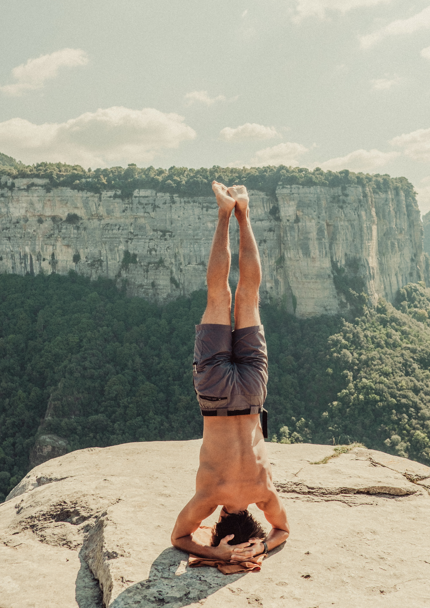 man doing yoga on a cliff